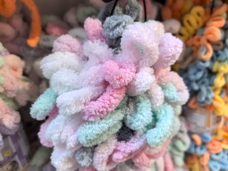 Soft and fluffy hair ties in pastel colors hang together, creating a playful and vibrant assortment. The warm atmosphere invites visitors to explore the delightful accessories.の写真素材