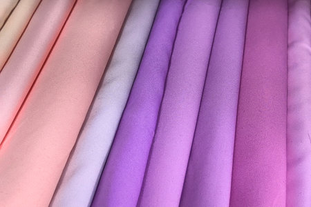 Rolls of soft pastel fabric lie neatly arranged, showcasing an array of calming hues from delicate pinks to rich purples.の写真素材