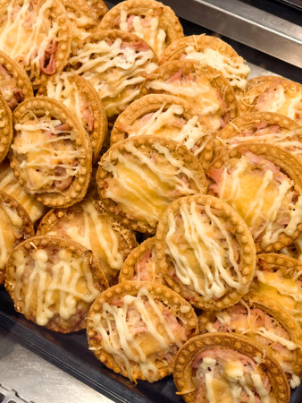 A delightful array of golden-brown pastries filled with creamy cheese and savory ham awaits hungry customers at a vibrant market stall during a bustling afternoon.の写真素材