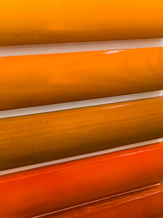 A colorful features display an array of yellow, orange, and warm hues arranged in horizontal stripes. The glossy surface reflects light, enhancing the vivid tones and textures.の写真素材