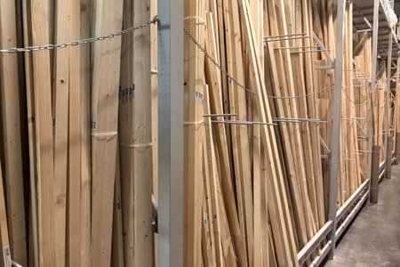 Rows of wooden planks stand tall and organized in a large home improvement store. Each piece is labeled, showing different sizes and types meant for various construction projects.の写真素材