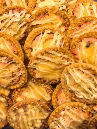 A delightful array of golden-brown pastries filled with creamy cheese and savory ham awaits hungry customers at a vibrant market stall during a bustling afternoon.の写真素材