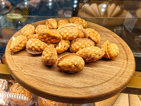 Golden, textured pastries rest on a wooden platter, inviting with their unique shape. Warm lights enhance their appeal in a cozy bakery, showcasing culinary artistry and tradition.の写真素材