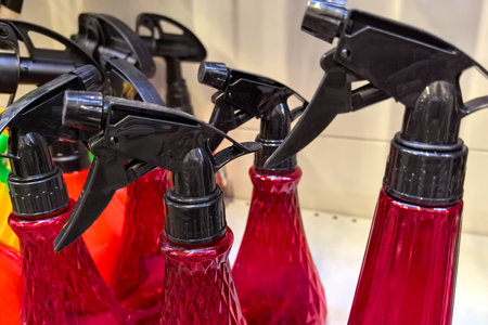 Brightly colored spray bottles with black trigger tops are lined up on a shelf in a retail space. Their vivid hues create an eye-catching arrangement that draws attention.の写真素材