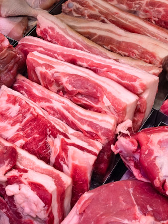 In a lively marketplace, vibrant cuts of pork display rich colors and textures. Vendors prepare the meat, while shoppers browse and select the freshest selections, creating an engaging atmosphere.の写真素材