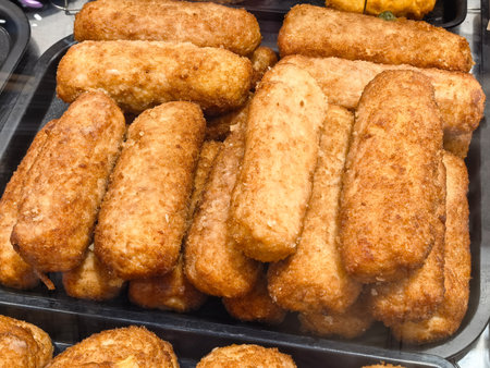 A vibrant display of crispy, golden snacks arranged in neat stacks at a busy street market. The...