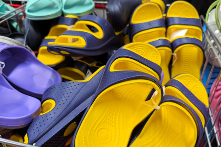 Bright yellow and navy sandals are stacked in a store display, showing their playful design....