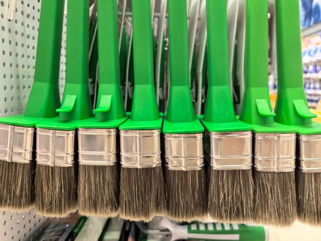A vivid array of green-handled paintbrushes is neatly displayed on a shelf in a craft store. Their bristles shine under warm lighting, inviting creativity and artistic exploration.の写真素材