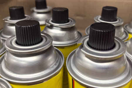 Several brightly colored cans are lined up on a shelf in a workshop. Their metallic tops shine under the light, indicating they are ready for various tasks and projects.の写真素材