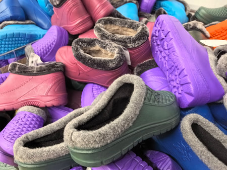 A lively assortment of soft, colorful footwear sprawls across the surface, showcasing shades of pink, blue, green, and purple with fuzzy linings for warmth and comfort.の写真素材