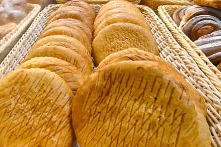 A tempting display of warm, golden loaves fills a wicker basket. The rustic texture and artisanal cuts suggest a skilled baker's touch, inviting passersby to indulge in fresh delights.の写真素材