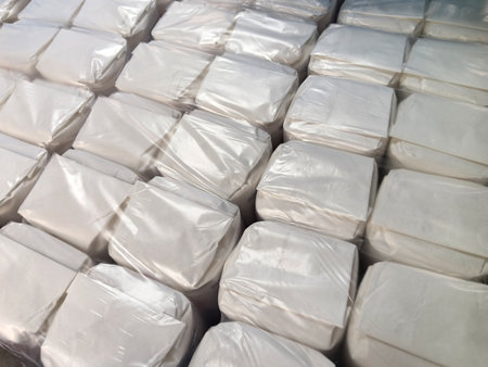 Rows of white packages are stacked tightly in a warehouse, surrounded by a clean and organized environment.の写真素材