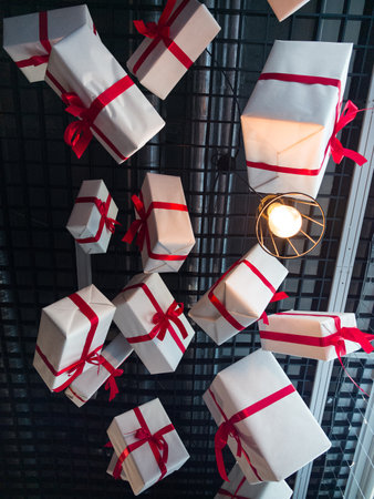 A delightful arrangement of wrapped gifts dangles from the ceiling, tied with vibrant red ribbons....