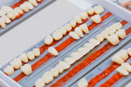 Rows of dentures arranged meticulously on a tray indicate the careful work in a dental lab. Each...