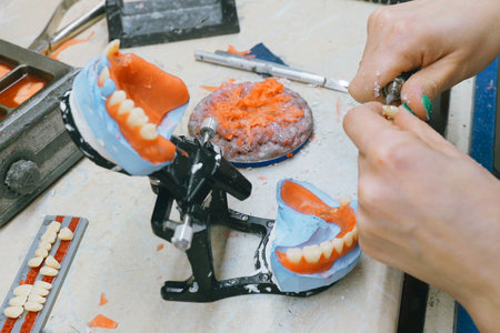 Expert dental technician skillfully shapes and grinds dentures in a dental lab. The meticulous process showcases attention to detail and craftsmanship in restoring smiles.の写真素材