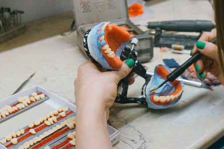 In a busy dental lab, a technician carefully molds and shapes dentures using wax and specialized...