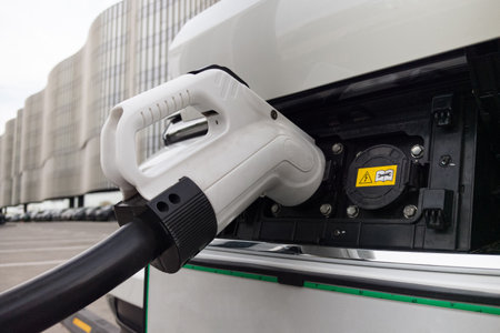 A sleek electric vehicle is being charged at a contemporary station. The structure features clean...