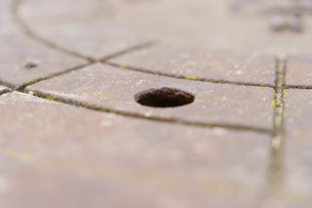 A weathered stone surface reveals intricate carvings and a small borehole, suggesting a historical...