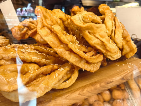 Golden, crispy treats beautifully arranged in a bakery display. The warm hues of sunset filter through, illuminating the textured surface, inviting passing customers to indulge in these delights.の写真素材