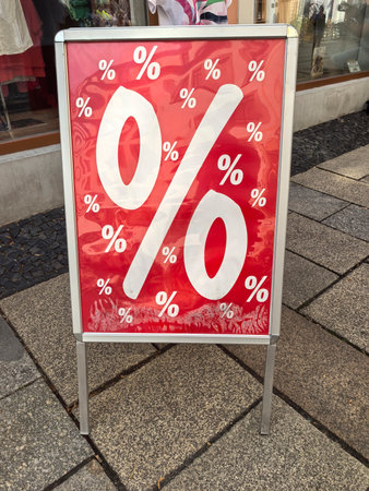 A vibrant red sign displaying large percentage symbols attracts attention in a bustling marketplace....