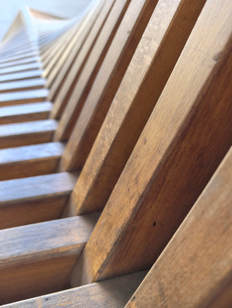 Warm tones of polished wood catch the sunlight, revealing a captivating pattern of slats. This unique design invites curiosity and showcases craftsmanship in a serene setting.の写真素材
