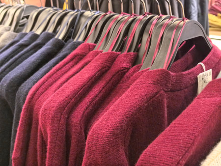 Rows of warm, richly colored sweaters hang neatly on black hangers, inviting shoppers to explore...