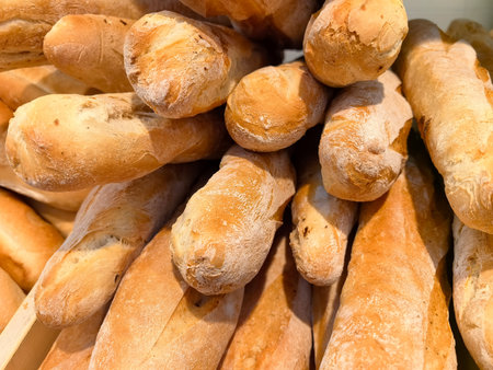 Golden-brown bread loaves are stacked together, showing their crusty exterior and soft interior. The...