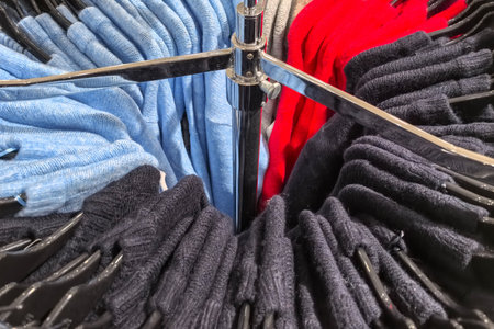 A collection of neatly folded sweaters in various colors is displayed on rotating racks. Shoppers...