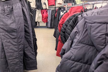 Shoppers explore a variety of warm clothing, featuring puffy jackets and comfortable pants arranged...