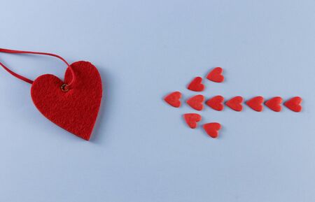 an arrow of red hearts points to a big heart on a blue background with place for textの写真素材