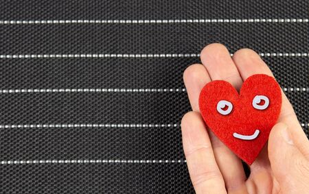 red heart with a smile in his hand on a black background. Valentines day concept.copyspace for text.