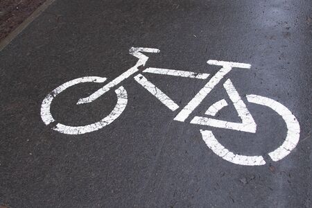 road bike sign white on wet pavement.