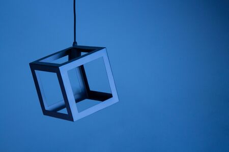metal lamp hanging on a wire on a blue background. square frame.の写真素材