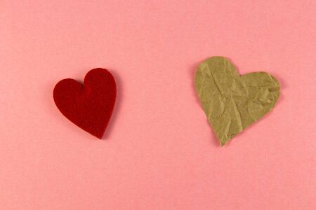crumpled paper in the shape of two hearts, small and large, on a pink background from natural paper....