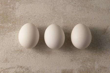 Three white chicken eggs on a blue background. place for text, easter holiday concept.