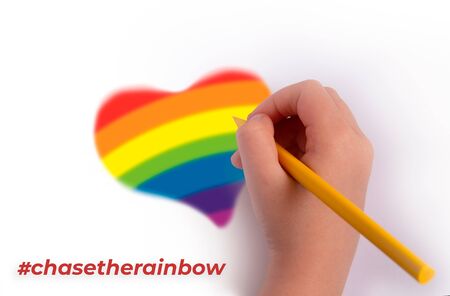 The concept of the pursuit of the rainbow. A hand with a pencil draws a heart in rainbow colors. inscription chasetherainbow.の写真素材