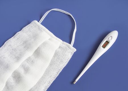 medical mask and medical thermometer. On a blue backgroundの写真素材