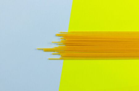 Raw pasta. yellow-blue background, spaghetti top view. Copyspace for text.の写真素材