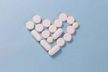Flat layout white heart shaped pills isolated on blue backgroundの写真素材