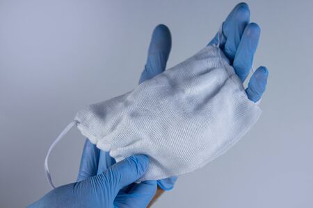Hands in gloves with a medical mask on a white background. Help and Protection Concept.の写真素材