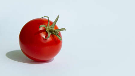 One red cherry tomato with green stems on a white background.copyspace for text.の写真素材