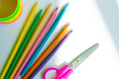 Colored pencils, scissors and container are located on a white background, top viewの写真素材