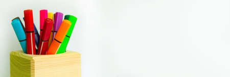 colored markers in a wooden container on a white background.copyspace for text.