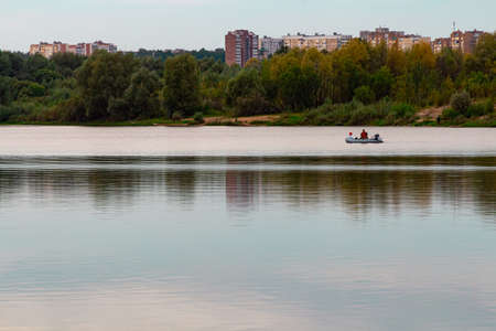 Two people in a pond on the background of the banks of the city with housesの写真素材
