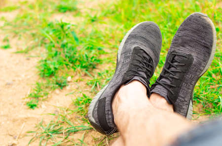Legs in sneakers on a background of sand and green grass. post workout rest conceptの写真素材