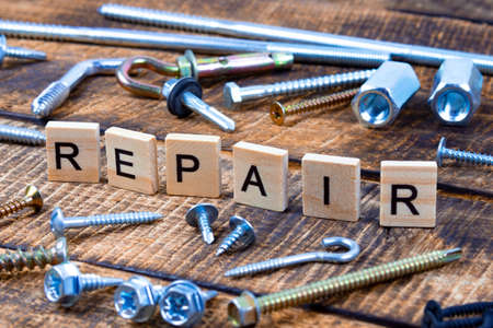 repair word on wooden background. Nuts, screws, nuts, flat washers are sealed. Diagonal orientationの写真素材