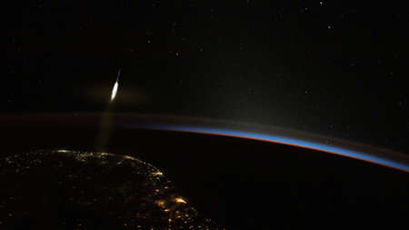 The rocket takes off from the earth into space. The planet is dark and night.