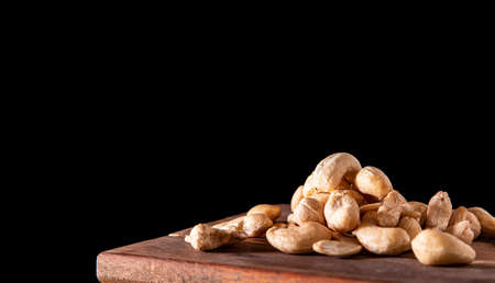 Cashew nuts piled in a pile on a wooden table side viewの写真素材