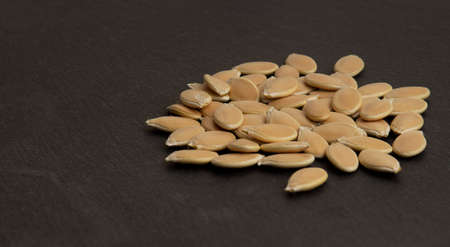 unpeeled pumpkin seeds piled in a pile on a dark surfaceの写真素材