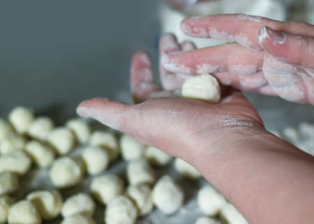 A woman sculpts Russian traditional ravioli dumplings. Hands twist balls of flourの写真素材